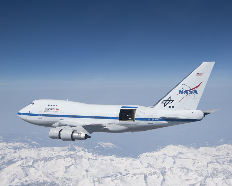 SOFIA se eleva sobre las montañas cubiertas de nieve de Sierra Nevada con la puerta de su telescopio abierta durante un vuelo de prueba. SOFIA es un avión Boeing 747SP modificado