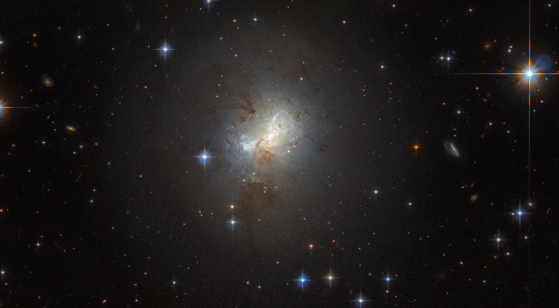 Ubicado en este campo de brillantes estrellas de primer plano, se encuentra ESO 495-21, una pequeña galaxia con un gran corazón. ESO 495-21 tiene solo 3000 años luz de diámetro, una fracción del tamaño de la Vía Láctea, pero eso no impide que la galaxia forme furiosamente grandes cantidades de estrellas